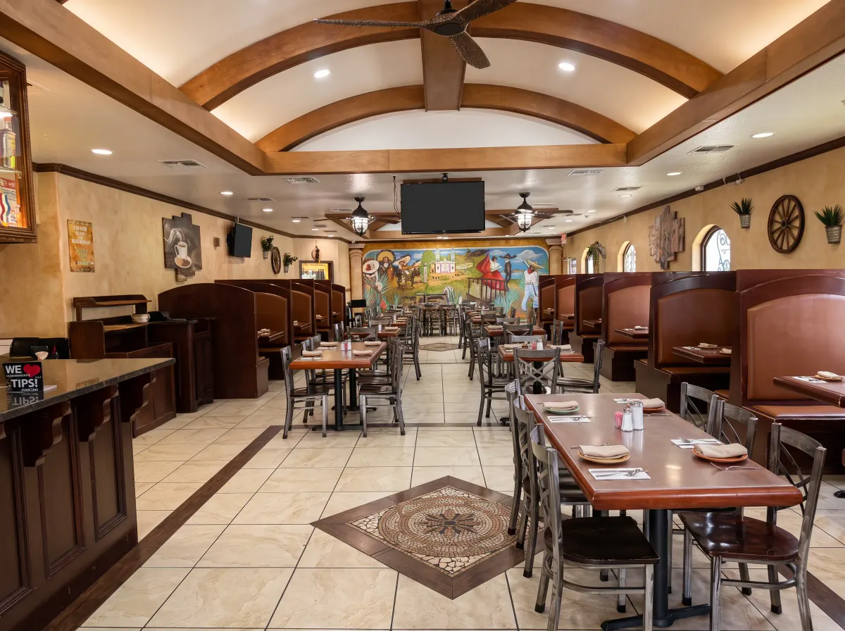 Jimador's main dining room under arched beams, with the hand-painted Jalisco mural at the far end