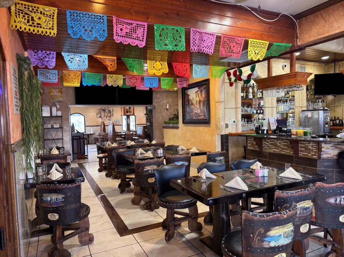 Dining room strung with papel picado beneath carved wooden beams